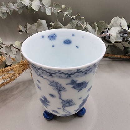 Footed Japanese porcelain sake cup with blue and white goldfish and lotus design.