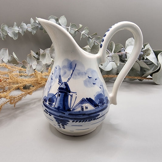 Small Delft porcelain jug with hand-painted blue windmill and house scene.