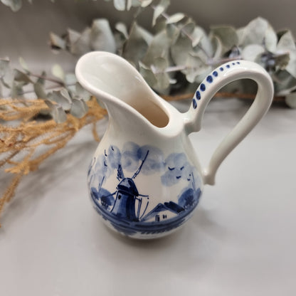 Small Delft porcelain jug with hand-painted blue windmill and house scene.