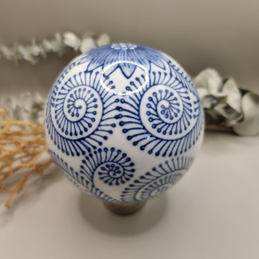 Blue and white ceramic sphere with spiral and floral patterns, decorative orb.