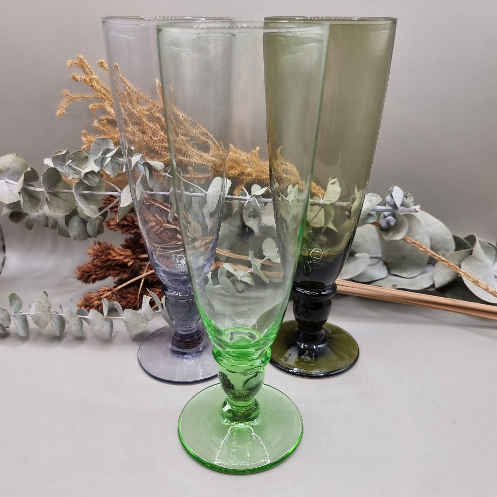 Set of 4 tall coloured glass flutes in green, grey, purple, and olive.

