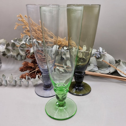 Set of 4 tall coloured glass flutes in green, grey, purple, and olive.

