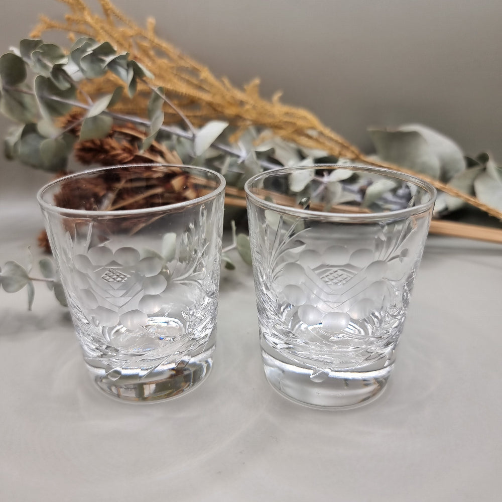 Pair of cut crystal shot glasses with etched floral and leaf pattern.