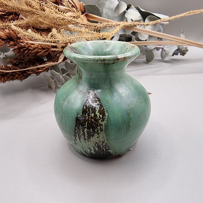 Small green glazed studio pottery vase with rustic brown accents.