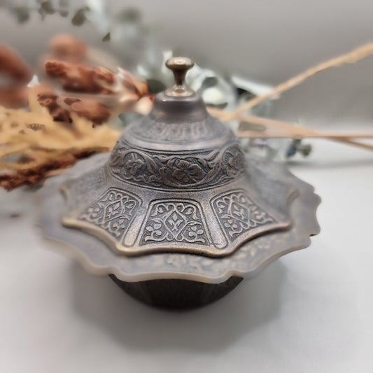 Ornate silver and gold-toned lidded metal trinket dish with embossed patterns.