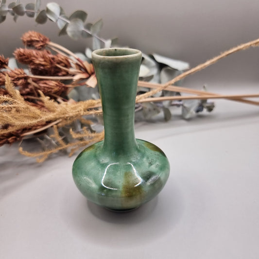 Small handmade green bud vase with narrow neck and rounded base.


