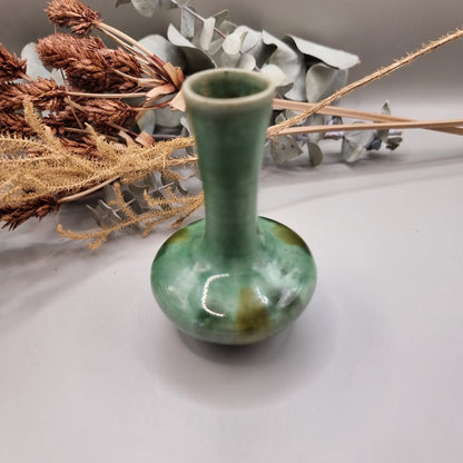 Small handmade green bud vase with narrow neck and rounded base.

