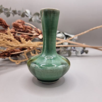 Small handmade green bud vase with narrow neck and rounded base.

