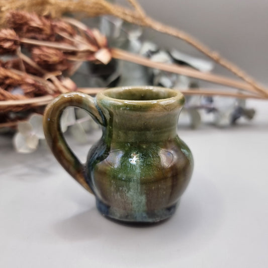 Small green glazed studio pottery jug with rounded shape and handle.