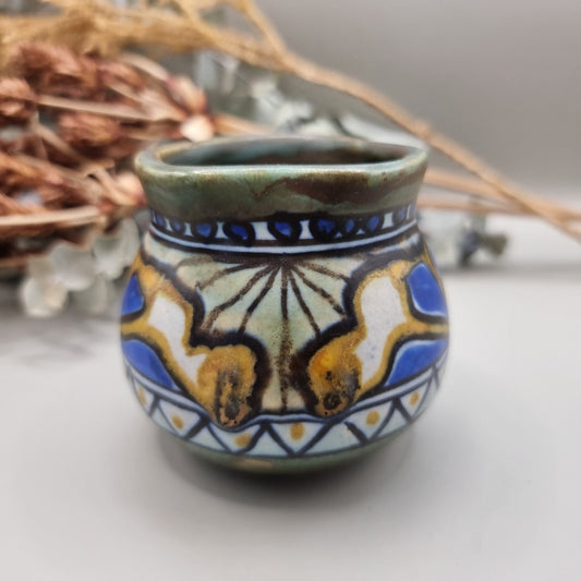 Small hand-painted ceramic pot with blue, gold, and green decorative pattern.
