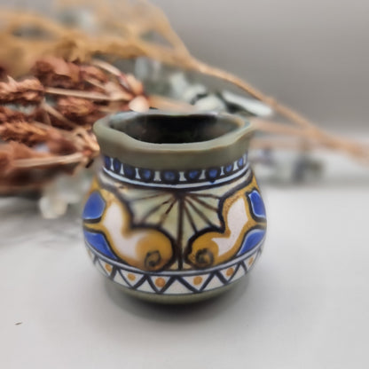 Small hand-painted ceramic pot with blue, gold, and green decorative pattern.