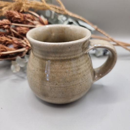 Handmade stoneware mug with sandy beige glaze and rounded belly shape