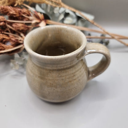 Handmade stoneware mug with sandy beige glaze and rounded belly shape