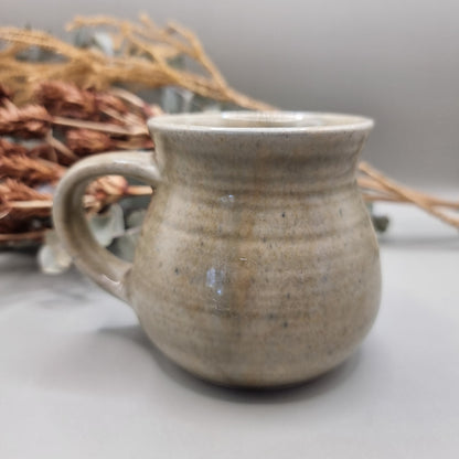 Handmade stoneware mug with sandy beige glaze and rounded belly shape