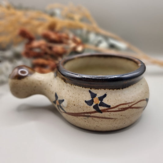 Small speckled soup bowl with painted floral vine and handle.