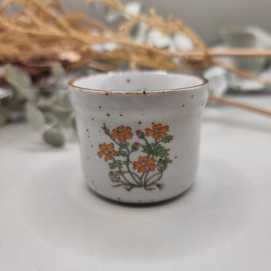 Mini speckled ceramic pot with orange floral design and bronze rim.