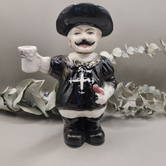 Vintage ceramic musketeer decanter holding a sword and stein with cork stopper and feathered hat.