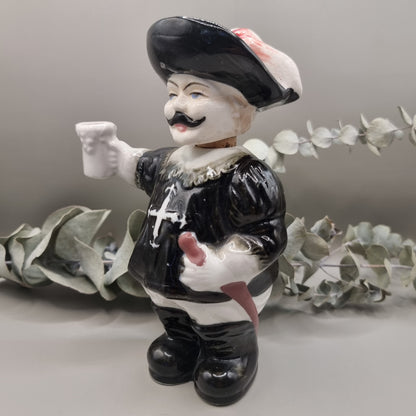 Vintage ceramic musketeer decanter holding a sword and stein with cork stopper and feathered hat.