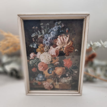 Vintage floral still life print in cream-toned frame with colourful bouquet.