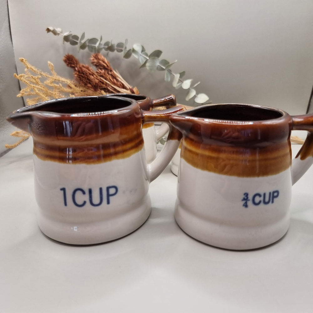 Vintage brown drip glaze stoneware measuring jugs set, marked ½ and ¼ cup.