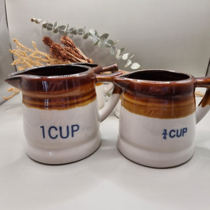 Vintage brown drip glaze stoneware measuring jugs set, marked ½ and ¼ cup.