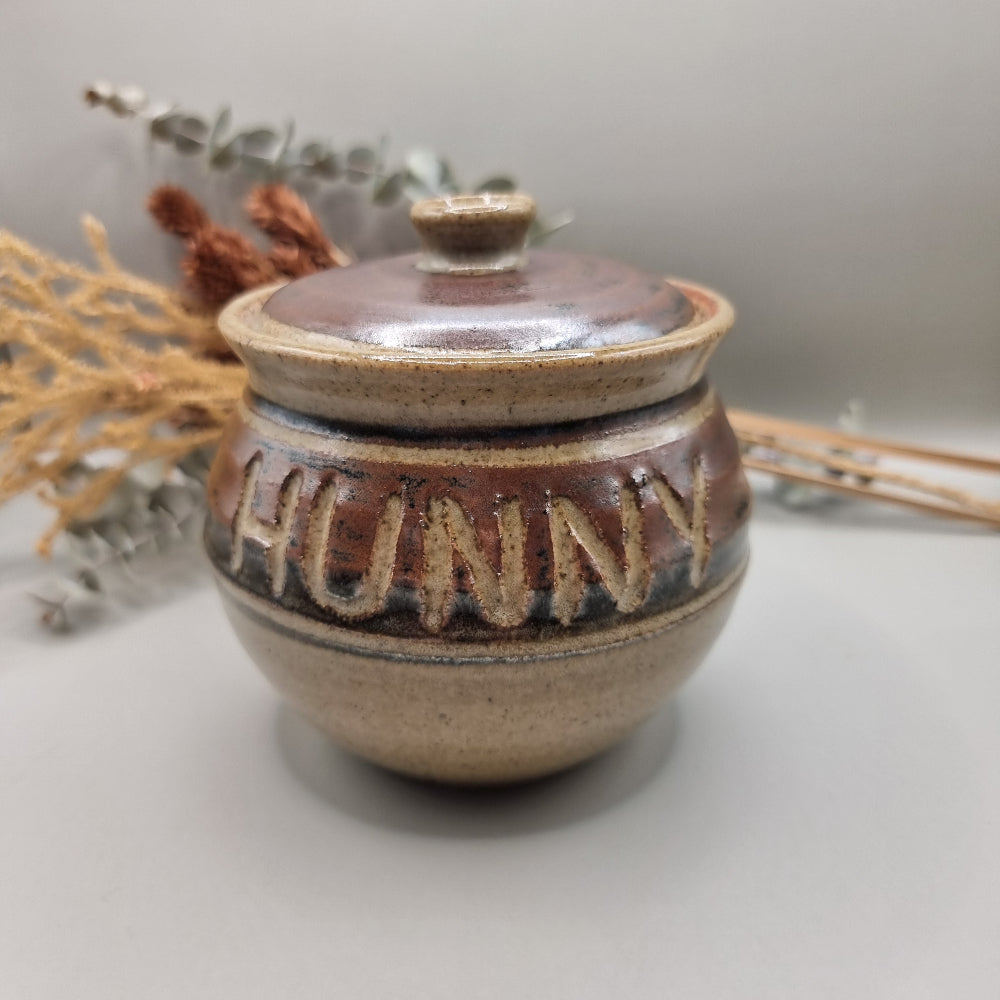 Vintage pottery honey pot with carved lettering reading “HUNNY”