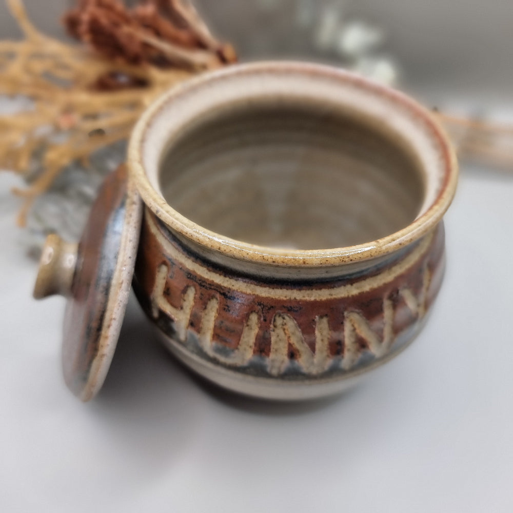 Vintage pottery honey pot with carved lettering reading “HUNNY”