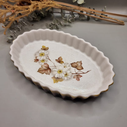 Vintage oval baking dish with scalloped edge and white daisy floral design in warm autumn tones