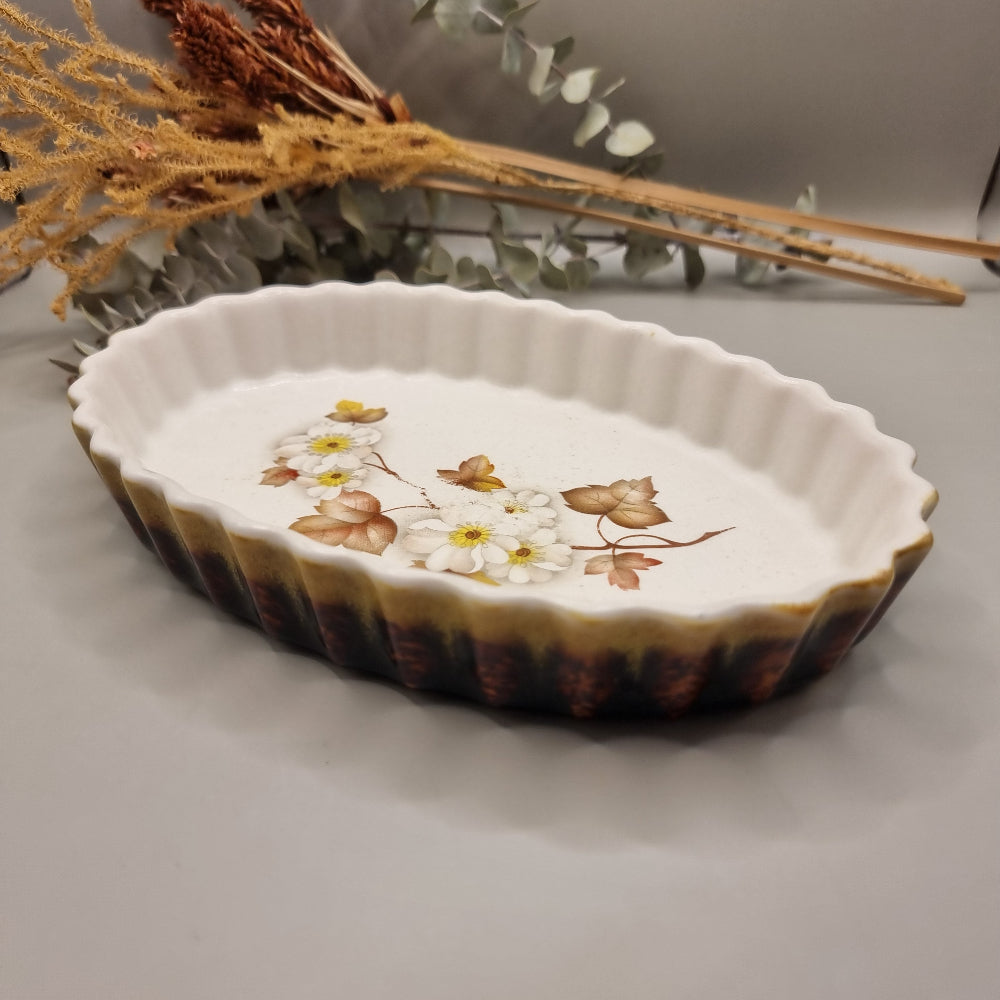Oval ceramic tart dish with white blossom and brown leaf design, scalloped edge and rustic glaze.