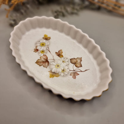 Oval ceramic tart dish with white blossom and brown leaf design, scalloped edge and rustic glaze.