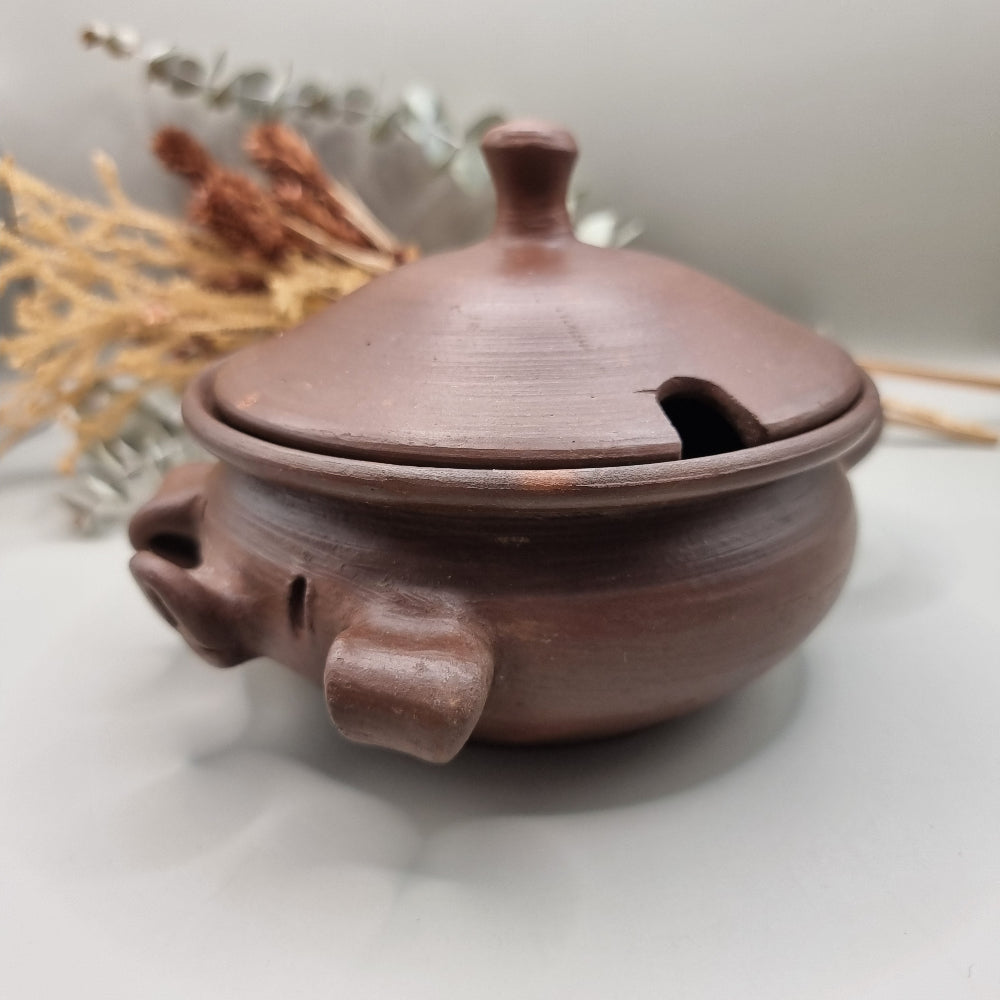 Handmade terracotta pig bowl with lid, ideal for salt or sugar storage in a rustic kitchen