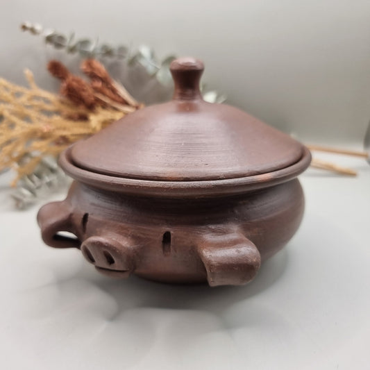 Handmade terracotta pig bowl with lid, ideal for salt or sugar storage in a rustic kitchen.