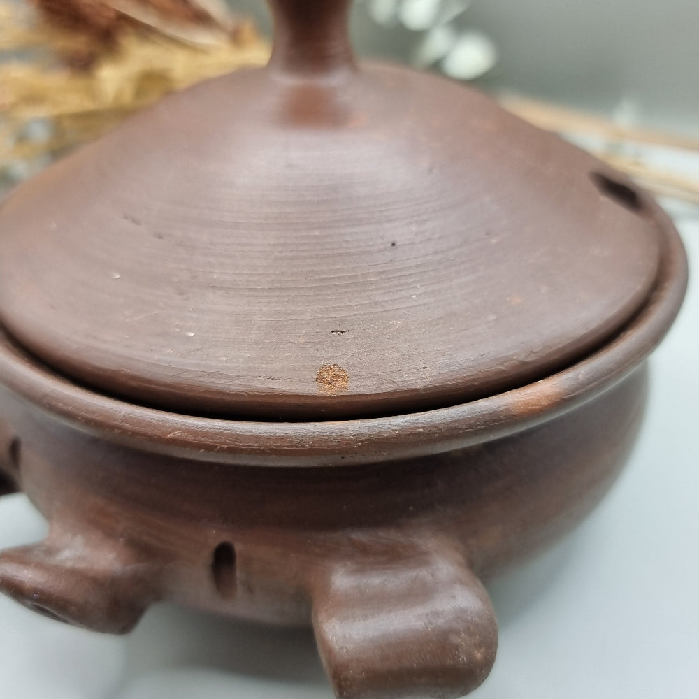 Handmade terracotta pig bowl with lid, ideal for salt or sugar storage in a rustic kitchen.