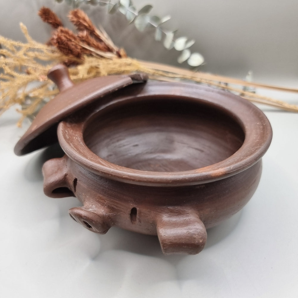 Handmade terracotta pig bowl with lid, ideal for salt or sugar storage in a rustic kitchen.