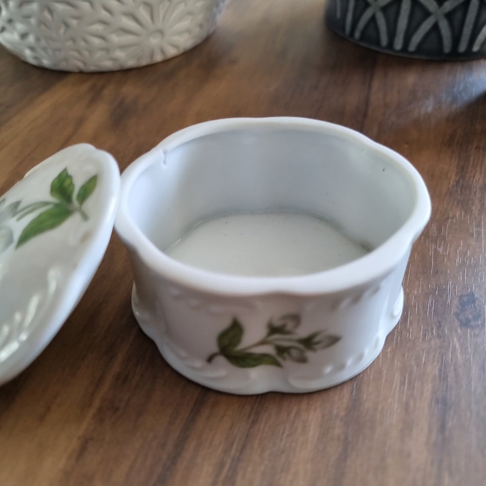 Vintage porcelain trinket box with scalloped edges and floral design featuring white flowers and green leaves