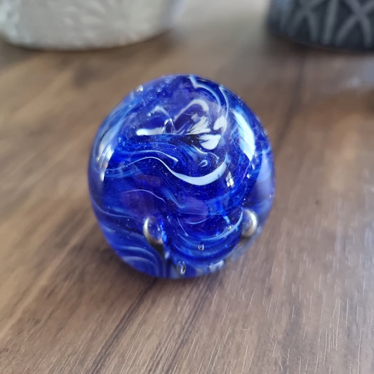 Cobalt blue swirl art glass paperweight with white and silver accents.