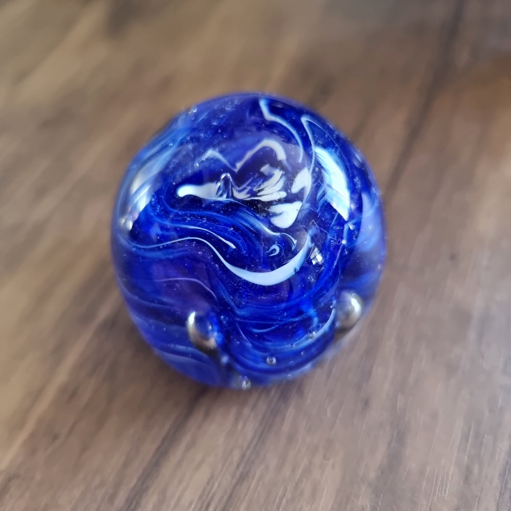 Cobalt blue swirl art glass paperweight with white and silver accents.