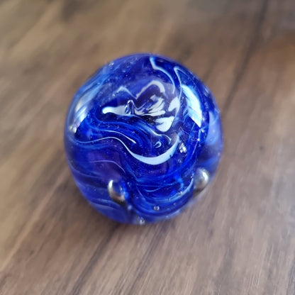 Cobalt blue swirl art glass paperweight with white and silver accents.