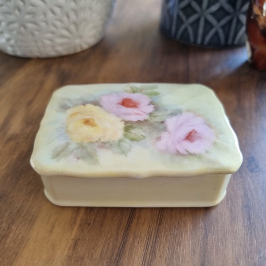 Porcelain trinket box with hand-painted pastel roses and scalloped edge lid.