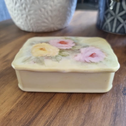 Porcelain trinket box with hand-painted pastel roses and scalloped edge lid.