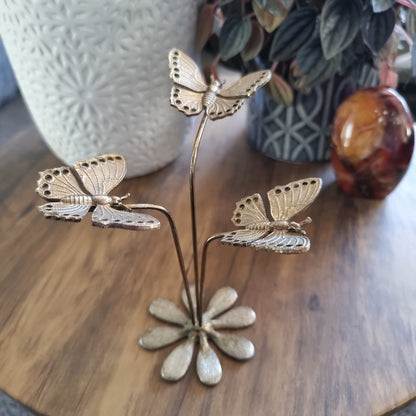 Gold butterfly earring holder with three butterflies on stems and daisy-style base.