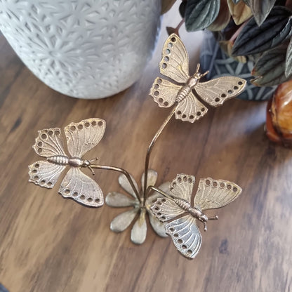 Gold butterfly earring holder with three butterflies on stems and daisy-style base.