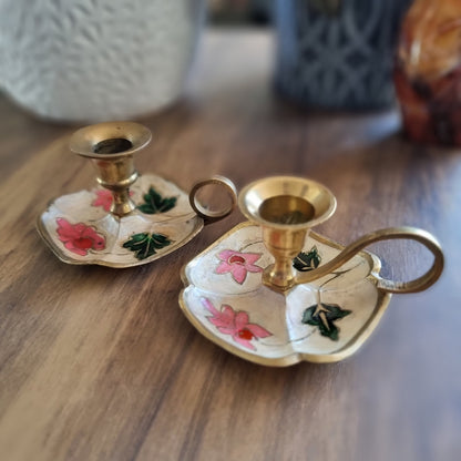 Pair of floral hand-painted brass chamberstick candle holders with loop handles.