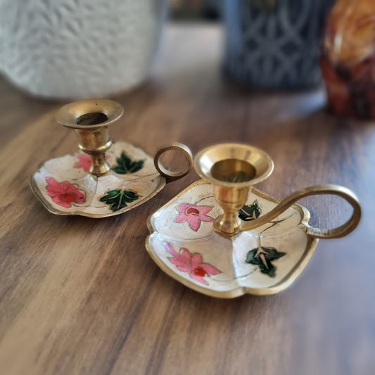 Pair of floral hand-painted brass chamberstick candle holders with loop handles.
