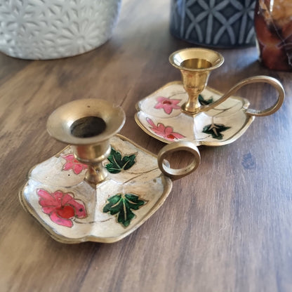 Pair of floral hand-painted brass chamberstick candle holders with loop handles.