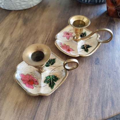 Pair of floral hand-painted brass chamberstick candle holders with loop handles.