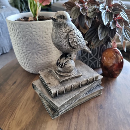 Rustic bird figurine perched on a stack of vintage-style books with a weathered stone finish