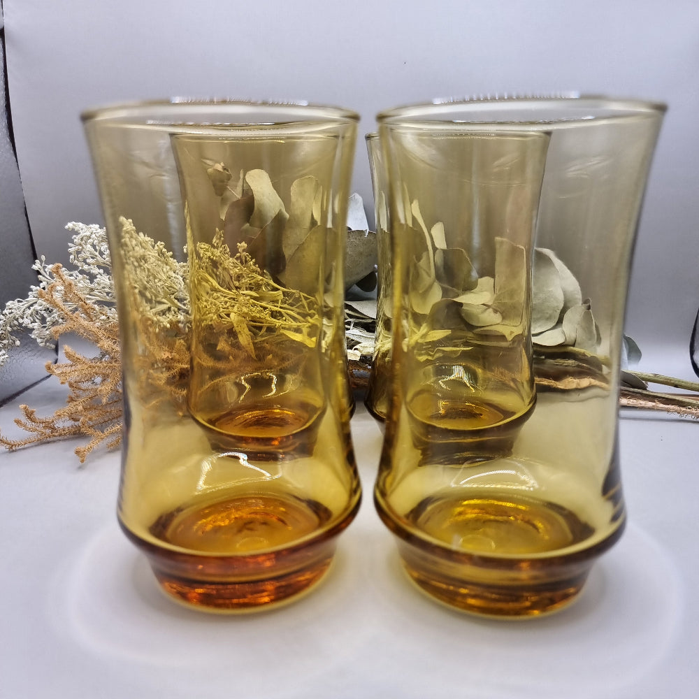 Set of four amber-coloured Kaaru retro glass tumblers with curved shape.