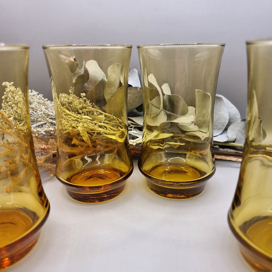 Set of four amber-coloured Kaaru retro glass tumblers with curved shape.