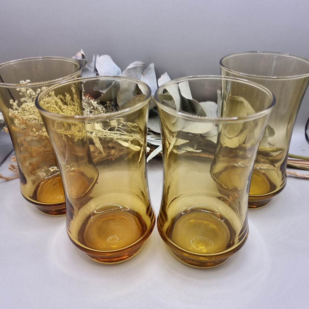 Set of four amber-coloured Kaaru retro glass tumblers with curved shape.